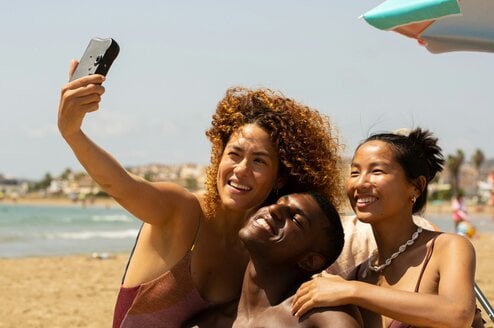 A group of friends take a selfie on the beach.