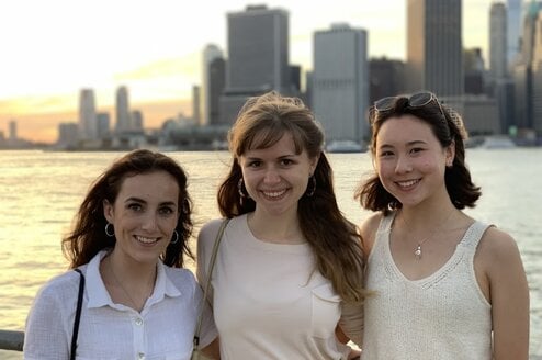 Three friends standing on a waterfront in a city